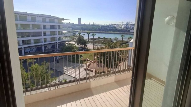 A balcony with a view of a cityscape, including buildings and a body of water. - THE ESCAPE FROM BOUREGREG (Salé)