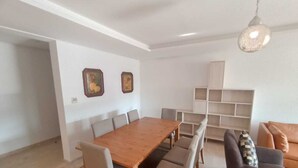 A modern living room with a wooden dining table, grey sofas, and a built-in shelving unit. - THE ESCAPE FROM BOUREGREG (Salé)