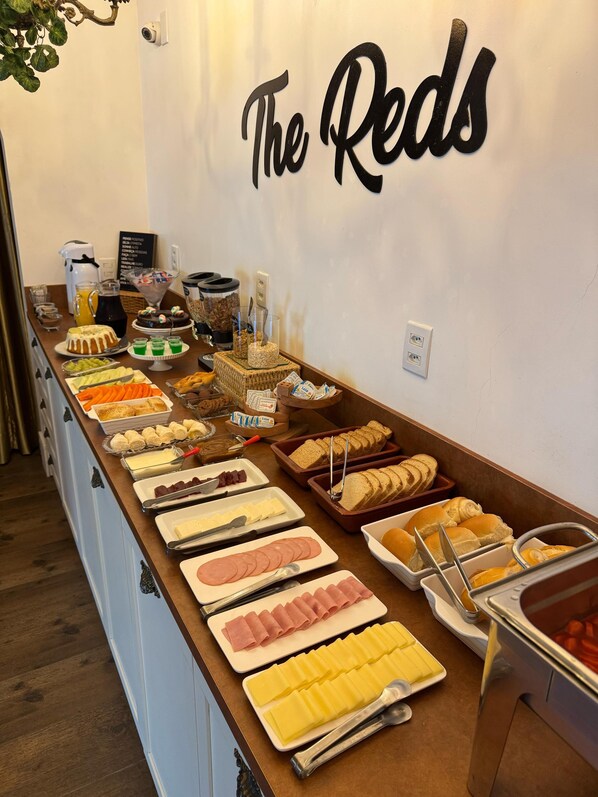 A buffet counter with various food items and a sign that reads "The Reds". - The Reds Pousada (Penha)