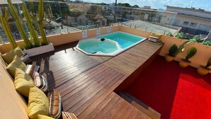 A rooftop terrace with a wooden deck, a hot tub, and potted plants. - The Reds Pousada (Penha)