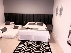 Ein Schlafzimmer mit zwei Betten, einem schwarz-weißen Teppich und einem Nachttisch mit Spiegel.