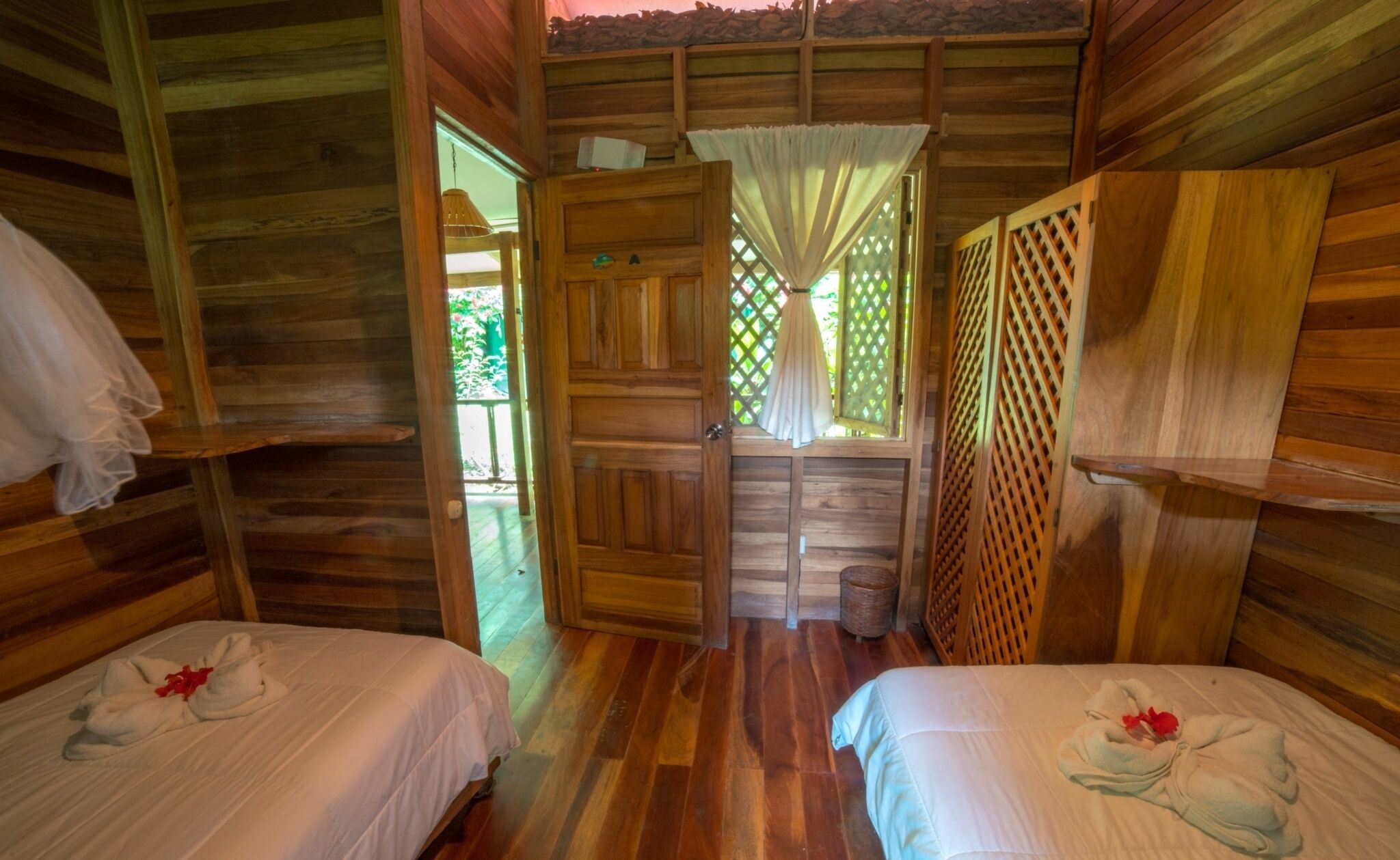 Una cabaña de madera con dos camas, cada una con una toalla y una flor.