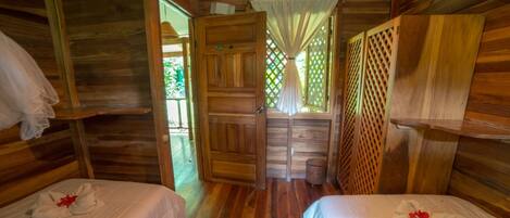 Una cabaña de madera con dos camas, cada una con una toalla y una flor.
