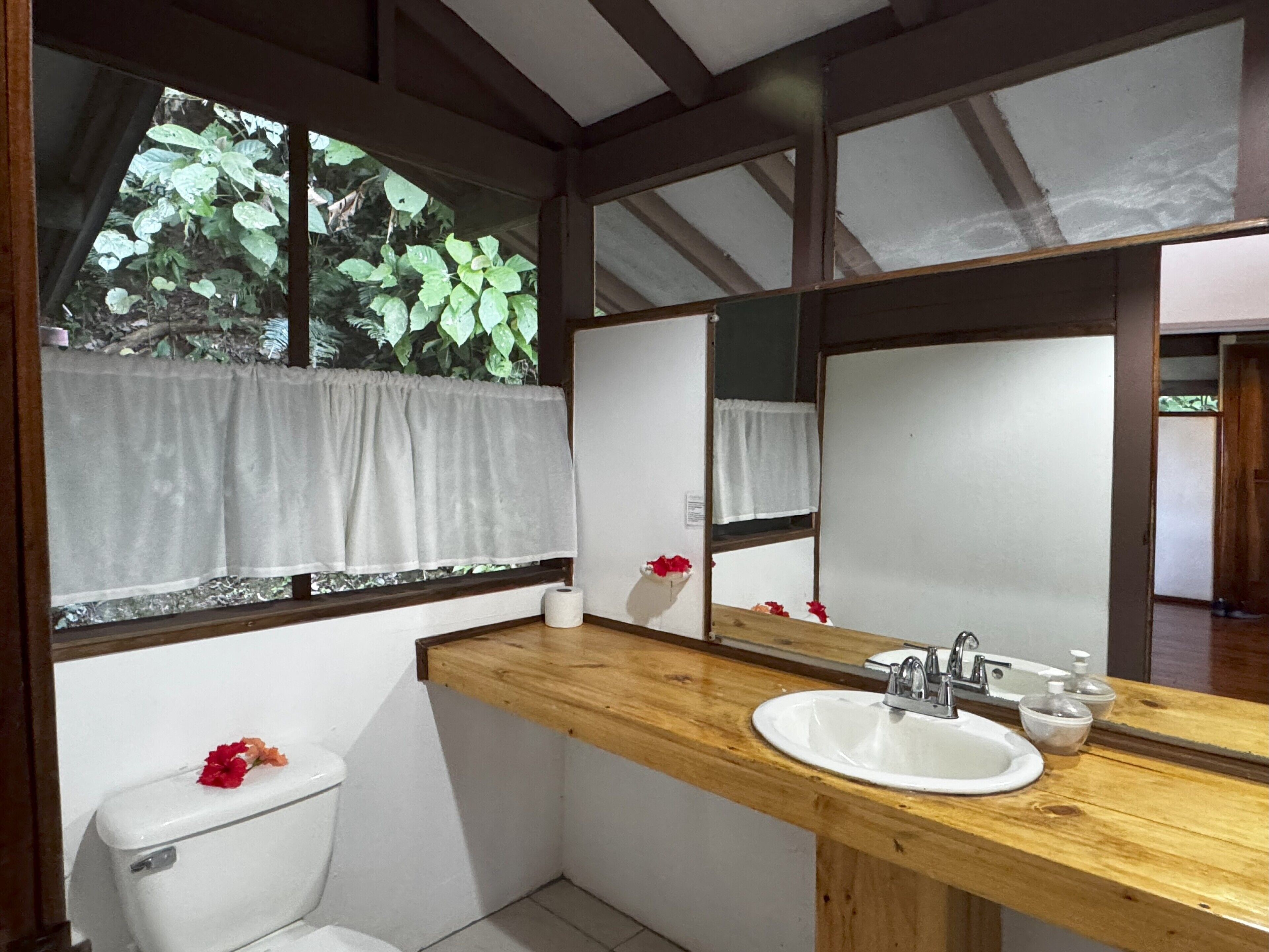 A bathroom with a wooden vanity, white sink, and a large mirror.
