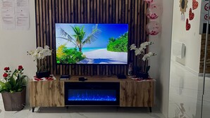 En platt-TV placerad på en möbel i trä, med en tropisk strandscen som bakgrund.