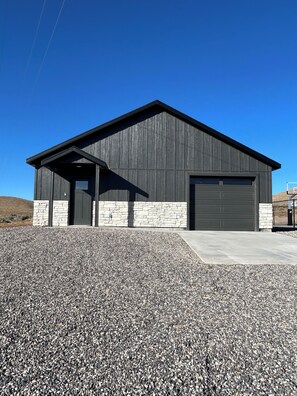 A modern building with a dark exterior, a stone base, and a large garage door. - The Lyman Getaway (Lyman)