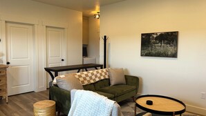 Ein gemütliches Wohnzimmer mit einem grünen Sofa, einem runden Couchtisch und einem Holznachttisch.