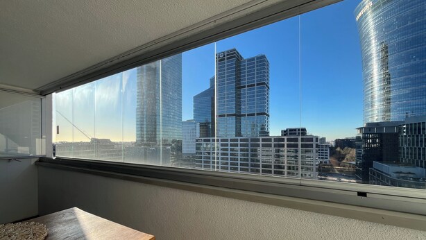 Ein Zimmer mit großem Fenster und Blick auf eine Skyline mit modernen Wolkenkratzern.