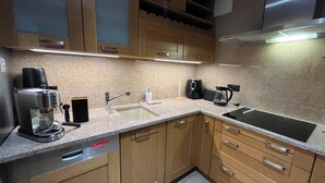 Eine Küche mit Holzschränken, einer Edelstahl-Spüle, einem Geschirrspüler von Bosch, einer Kaffeemaschine und einem Toaster.