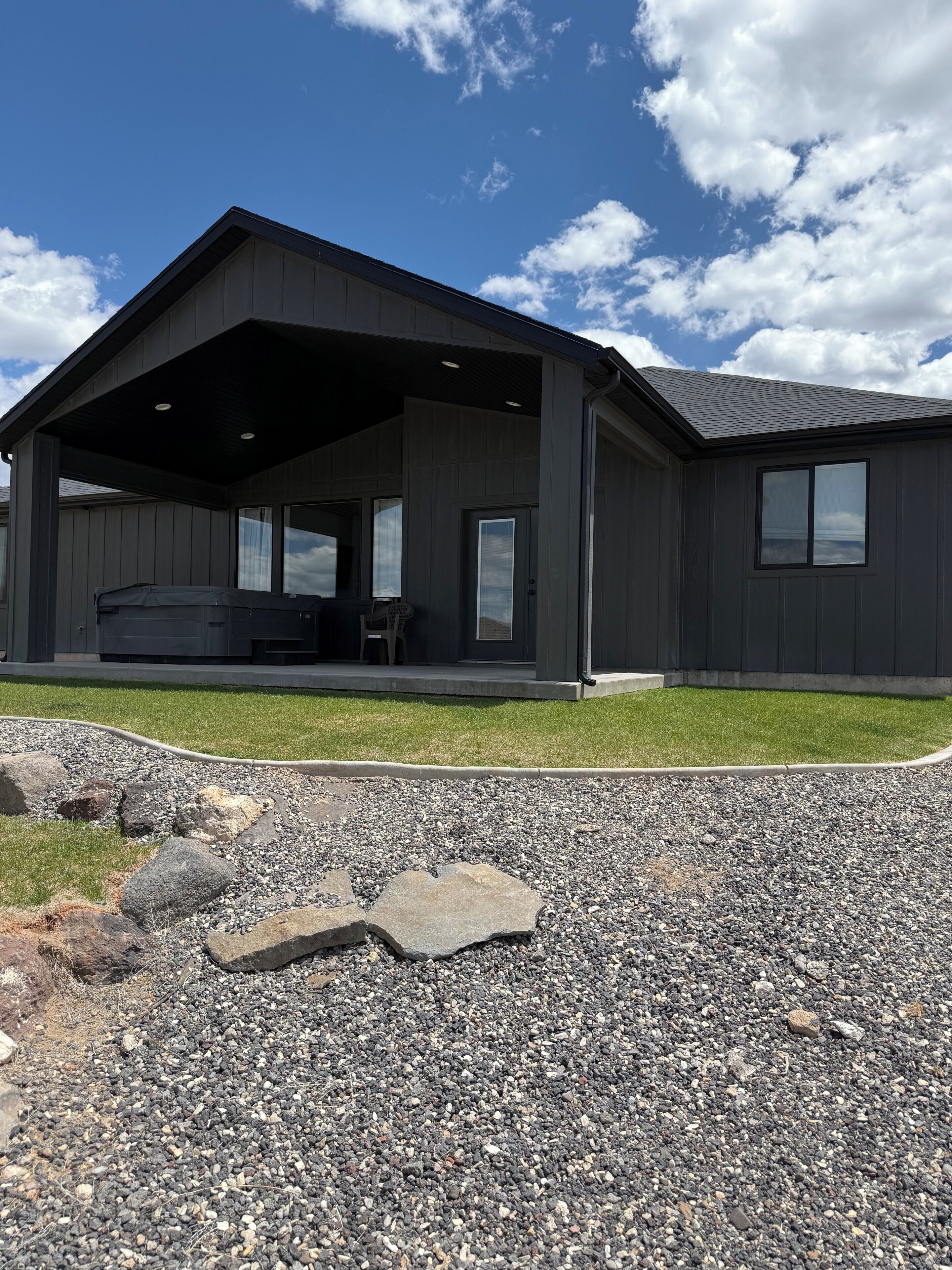 A modern building with a covered porch, a stone pathway, and a clear sky.