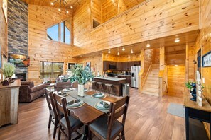 Una cabaña de madera espaciosa con comedor, cocina y sala de estar.