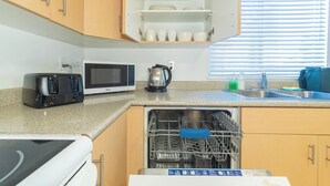 A kitchen with a microwave, toaster, kettle, and dishwasher.