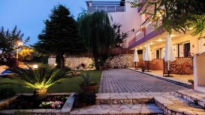 A courtyard with stone steps, a lawn, and a building with a balcony. - Studio Apartment 'Two Adults No 1' with Sea View, Wi-Fi and Air Conditioning (Nikiana)
