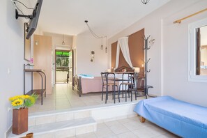 A room with a bed, a dining table with chairs, a TV mounted on the wall, and a staircase leading to another room. - Studio Apartment '3 Adults No 3' with Sea View, Wi-Fi and Air Conditioning (Nikiana)