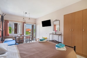 A bedroom with a bed, a desk, a chair, a TV, and a wardrobe. - Studio Apartment '3 Adults No 3' with Sea View, Wi-Fi and Air Conditioning (Nikiana)
