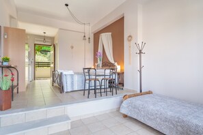 Une chambre à coucher avec un lit, un bureau avec des chaises, un porte-manteau et une vue sur l’extérieur.