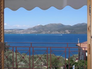Vista costera con cielo despejado, masa de agua y montañas distantes.