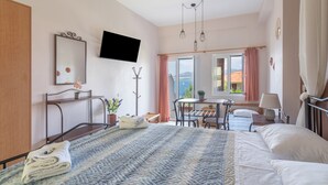 A hotel room with a bed, a desk, a chair, a TV, and a window with a view. - Studio Apartment '3 Adults No 5' with Sea View, Wi-Fi and Air Conditioning (Nikiana)