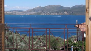 A coastal view from a balcony with a metal railing, a clear blue sea, and distant mountains. - Studio Apartment '3 Adults No 5' with Sea View, Wi-Fi and Air Conditioning (Nikiana)