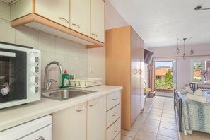 Una cocina con horno empotrado, un fregadero y ventana con vista a un balcón.