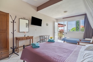 A bedroom with a bed, a desk, a chair, a television, and a view of the outdoors. - Studio Apartment '4 Adults No 10' with Sea View, Wi-Fi and Air Conditioning (Nikiana)