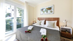 Habitación de hotel con una cama grande, una obra de arte con un mapa del mundo, una ventana con vista a follaje y una mesita de noche con una lámpara.