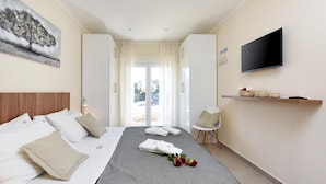 Una habitación de hotel con cama, televisor, escritorio y ventana con cortinas.