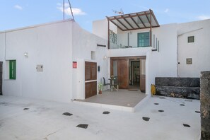 A two-story building with a balcony, a door, and a small table with chairs.