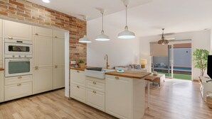 A modern kitchen with white cabinets, a brick accent wall, and pendant lighting.