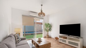 A living room with a sofa, coffee table, TV, and a plant.