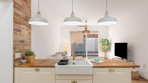 A kitchen with a wooden countertop, a white sink, and three pendant lights.