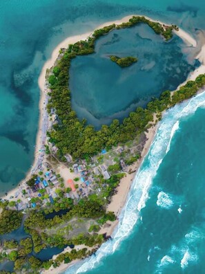 Oversigtsbillede af et kystområde med en strand, frodig vegetation og spredte huse.