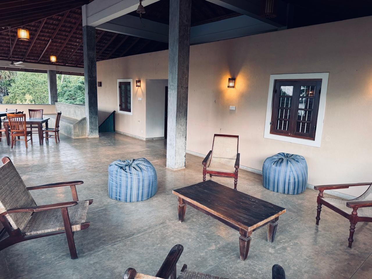 A spacious indoor area with a high ceiling, concrete flooring, and several wooden chairs and tables.