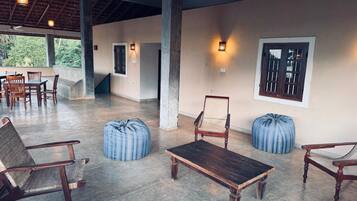 A spacious indoor area with a high ceiling, concrete flooring, and several wooden chairs and tables.