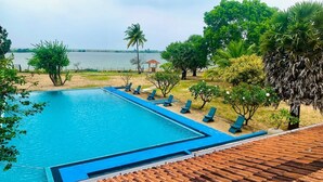 A swimming pool with lounge chairs and a view of the water. - Dinuda Villas Kalpitiya  (Kalpitiya)