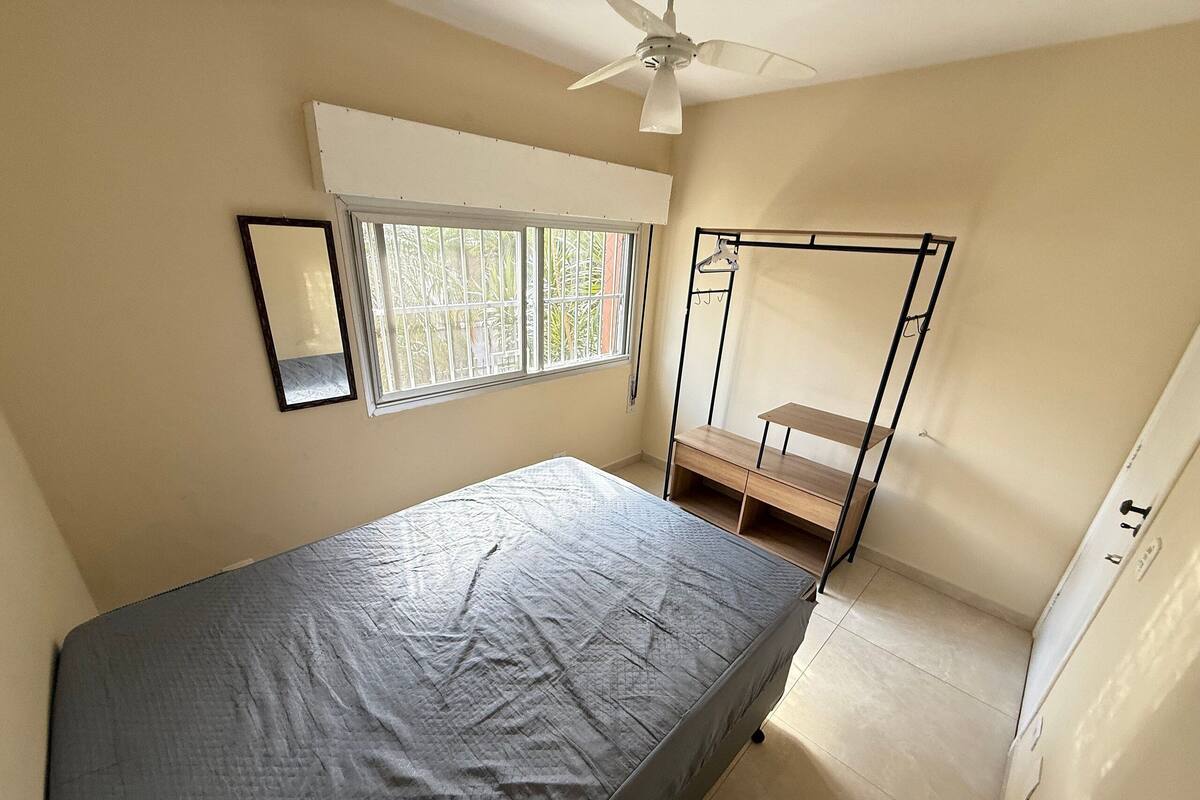 A bedroom with a bed, a window, a ceiling fan, and a wardrobe.
