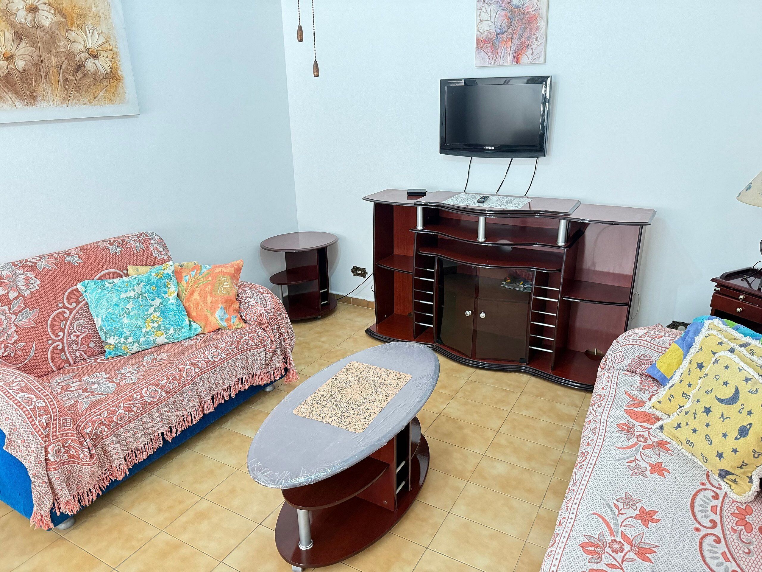 A living room with a sofa, a coffee table, a TV, and a wooden entertainment unit.