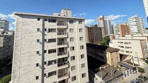 A multi-story residential building with balconies, a visible antenna, and a clear sky. - Pé na Areia Praia do Canto do Forte IV (Praia Grande)