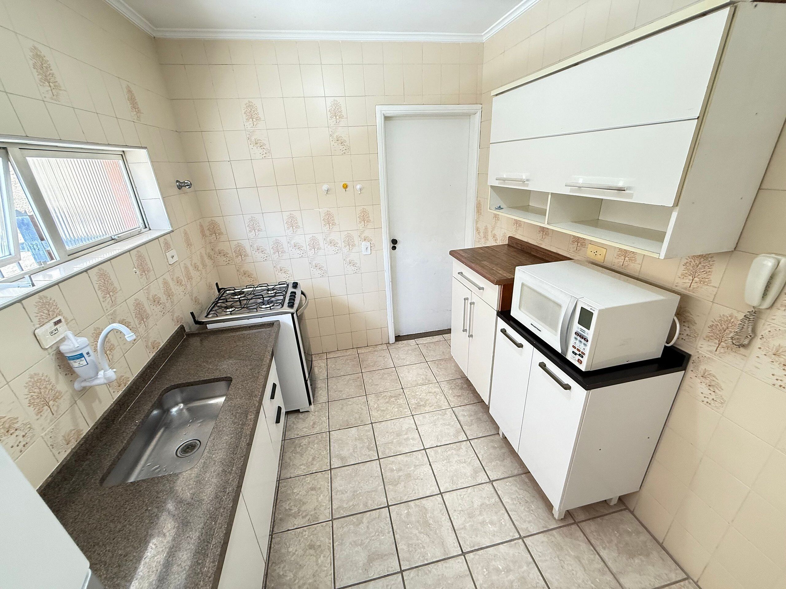 A compact kitchen with a gas stove, a microwave, a sink, and a small countertop.