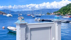 Un puerto deportivo con varias embarcaciones amarradas, cielo azul despejado y montañas al fondo.
