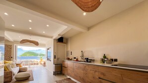 Una cocina moderna con encimera de madera, horno empotrado y vistas al mar a través de la puerta abierta.