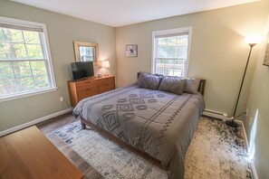 A bedroom with a bed, dresser, TV, and two windows. - Okemo mountain house with private hot tub (Ludlow)