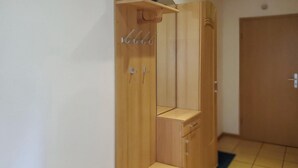 Un armario de madera con barra para colgar y un pequeño estante.