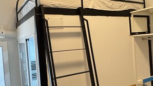 A bunk bed with a ladder, a small window, and a white door. - Hostal Ruano (Madrid)
