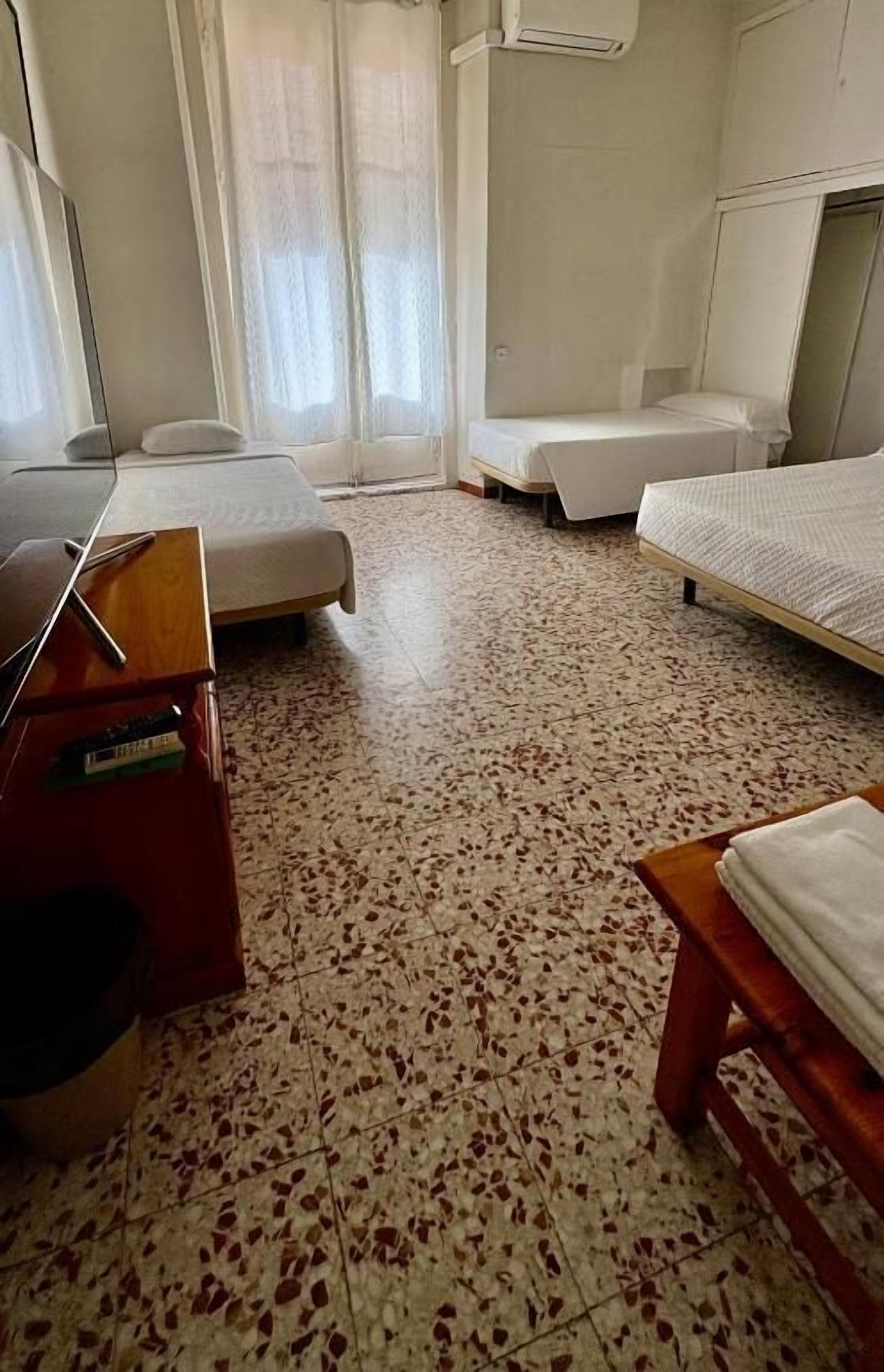 A hotel room with two beds, a desk, and a chair.