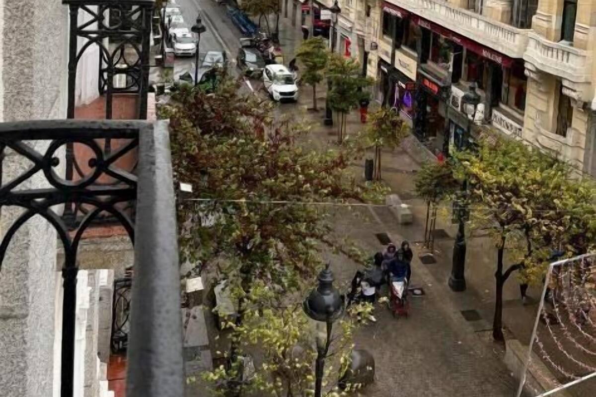 Straatbeeld met gebouwen, een heldere lucht en enkele voetgangers.