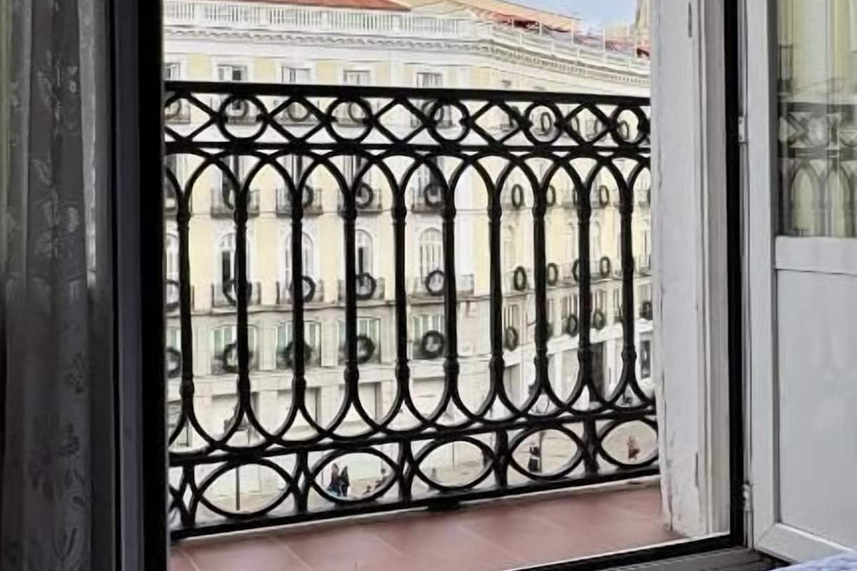 Een balkon met een ijzeren hekwerk en uitzicht op historische gebouwen.