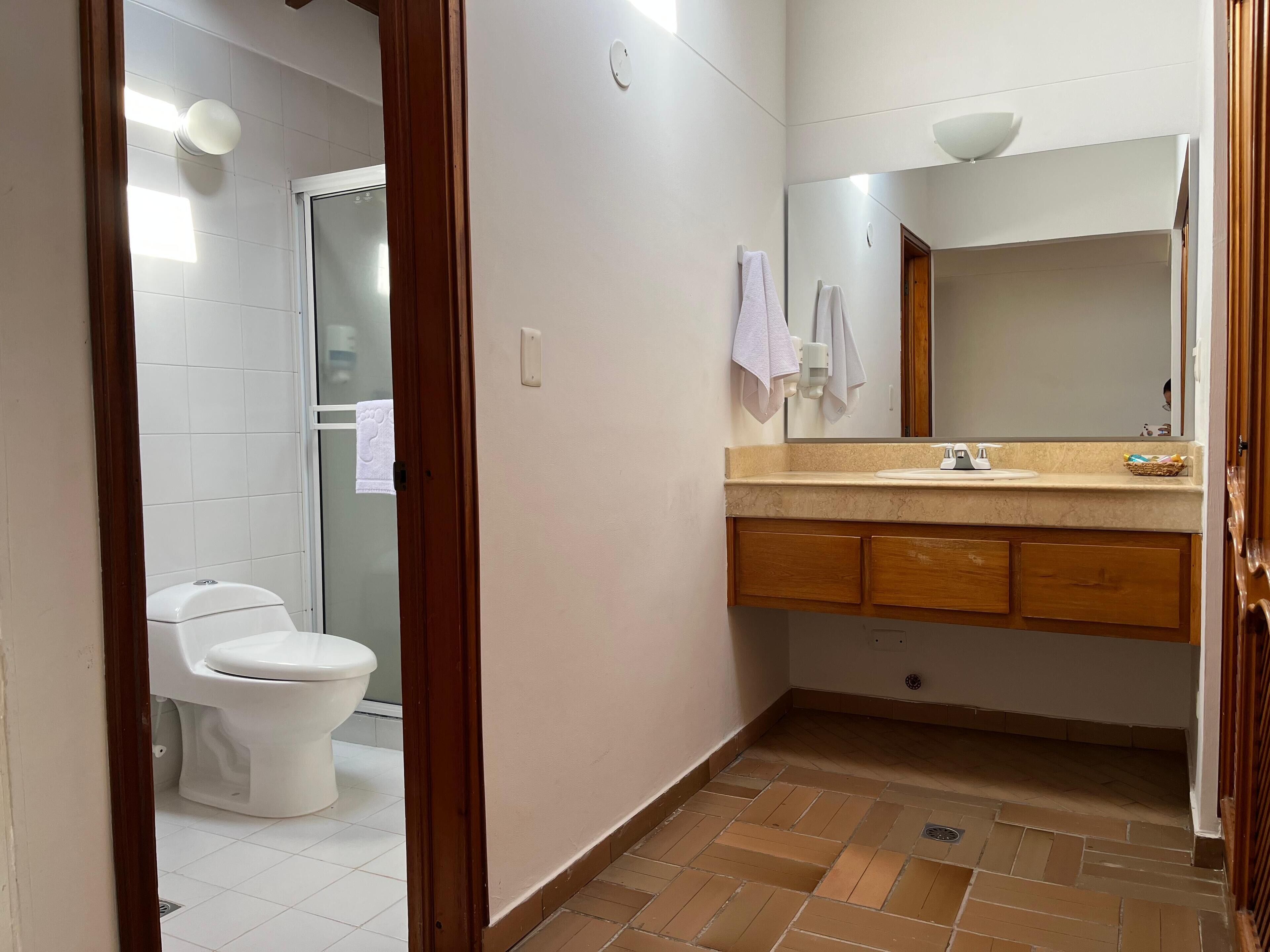 A bathroom with a toilet, a sink with a mirror, and a tiled floor.