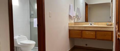 A bathroom with a toilet, a sink with a mirror, and a tiled floor.