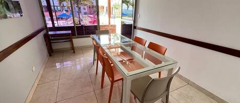 Un salón de conferencias con una mesa y sillas de vidrio, amplias ventanas que dan a un patio al aire libre.